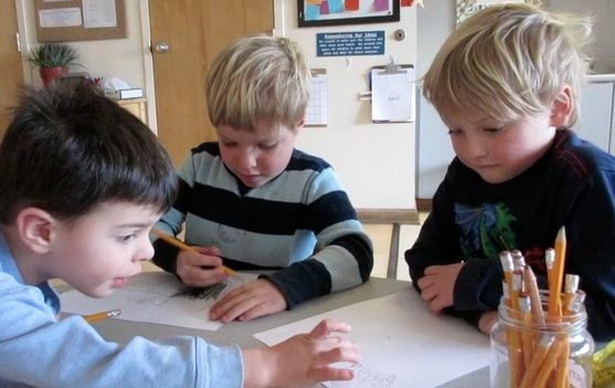 Three four year old boys writing numbers